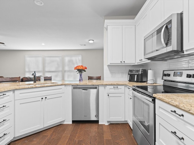 kitchen featuring white cabinets, a sink, dark wood finished floors, stainless steel appliances, and tasteful backsplash