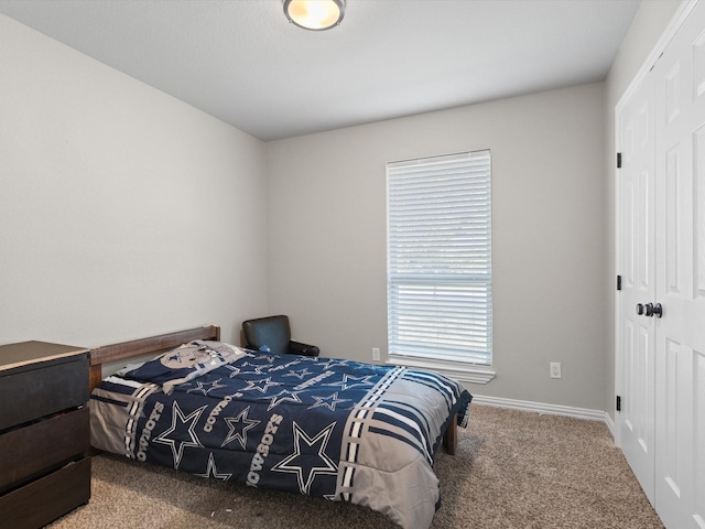 carpeted bedroom with a closet and baseboards