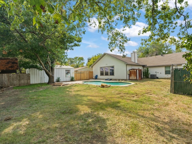 rear view of property with an outdoor structure, a fenced backyard, a lawn, and a shed