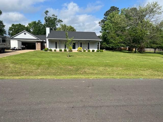 ranch-style home with concrete driveway, a chimney, a front yard, and a garage