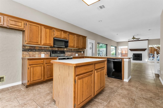 3813 Parkmont Dr, Plano, TX 75023 - kitchen with a center island, a fireplace, visible vents, ceiling fan, and black appliances
