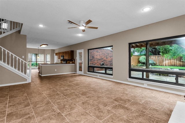 3813 Parkmont Dr, Plano, TX 75023 - unfurnished living room featuring a ceiling fan, stairs, baseboards, and a healthy amount of sunlight