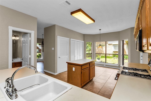 3813 Parkmont Dr, Plano, TX 75023 - kitchen with light tile patterned floors, visible vents, a sink, brown cabinets, and light countertops