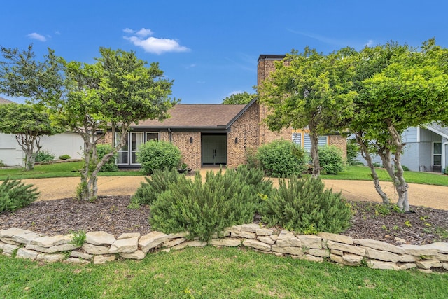 ranch-style house featuring brick siding, a front lawn, and a chimney