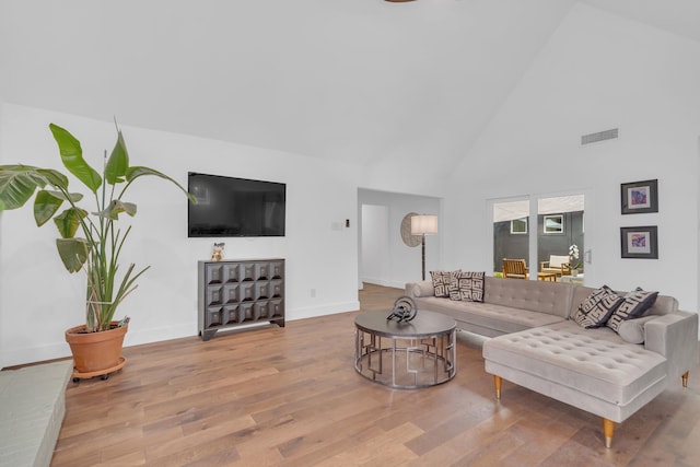 living room featuring high vaulted ceiling, baseboards, wood finished floors, and visible vents
