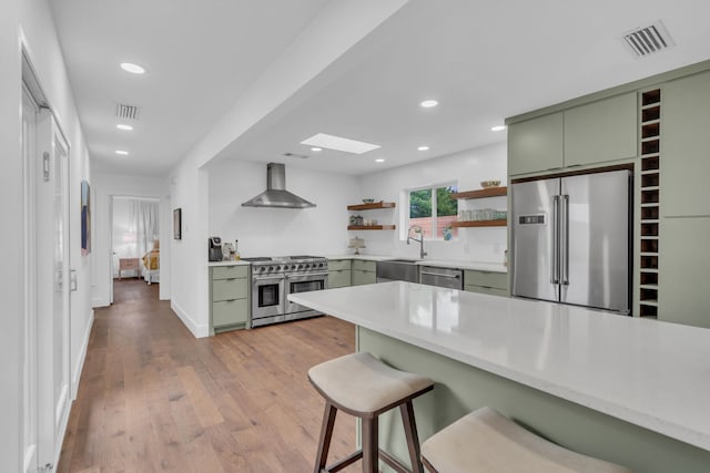 kitchen featuring visible vents, open shelves, high quality appliances, wall chimney exhaust hood, and green cabinets