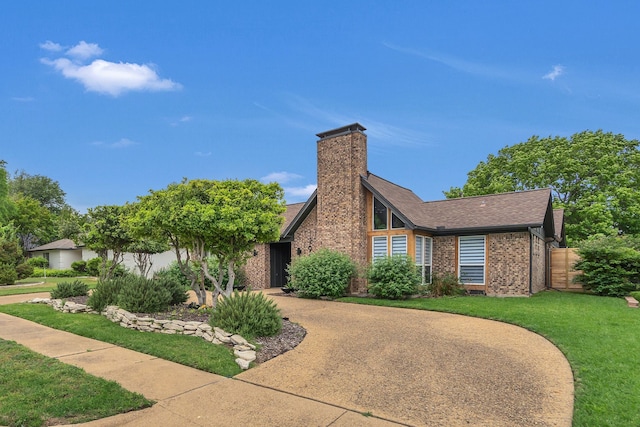 view of front of home featuring brick siding, a front lawn, roof with shingles, and a chimney