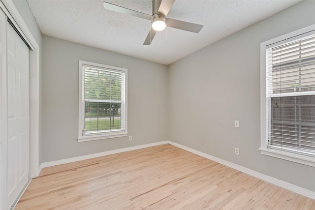 unfurnished bedroom with baseboards, multiple windows, a closet, and wood finished floors