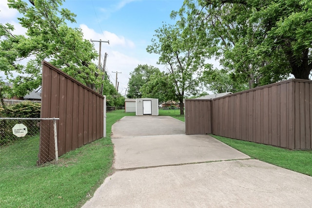 exterior space with a storage shed, fence, an outbuilding, and driveway
