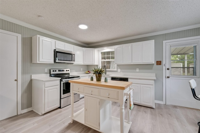 kitchen with crown molding, a textured ceiling, appliances with stainless steel finishes, and light wood-type flooring