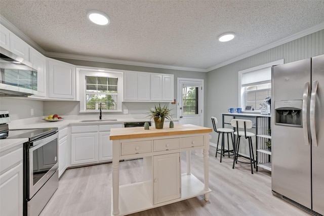 kitchen featuring crown molding, a textured ceiling, appliances with stainless steel finishes, and a sink