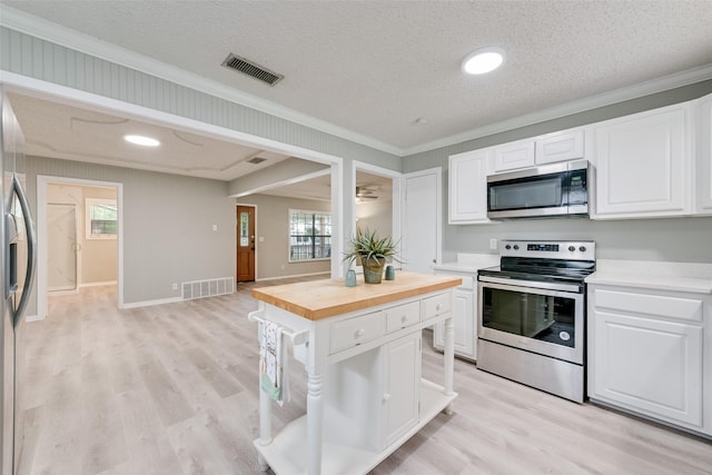 kitchen with wooden counters, ornamental molding, stainless steel appliances, and visible vents