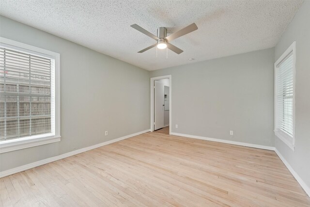 empty room with plenty of natural light, ceiling fan, and wood finished floors