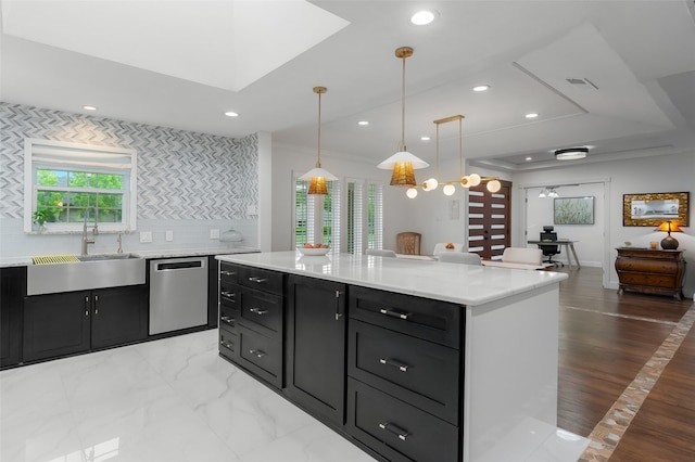 kitchen featuring a sink, dark cabinets, stainless steel dishwasher, visible vents, and pendant lighting