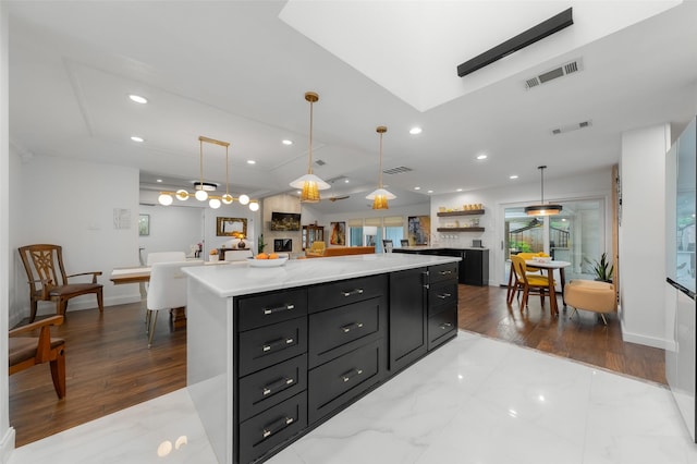 kitchen with visible vents, a kitchen island, open floor plan, recessed lighting, and dark cabinetry