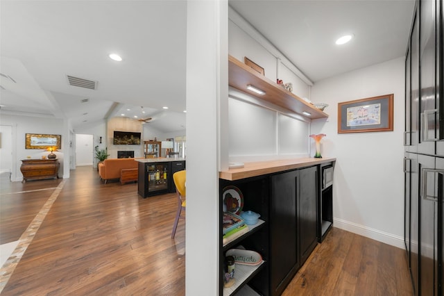 kitchen featuring visible vents, a large fireplace, open shelves, baseboards, and dark wood-type flooring