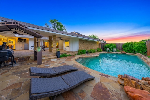 pool at dusk featuring a fenced in pool, a fenced backyard, ceiling fan, and a patio area