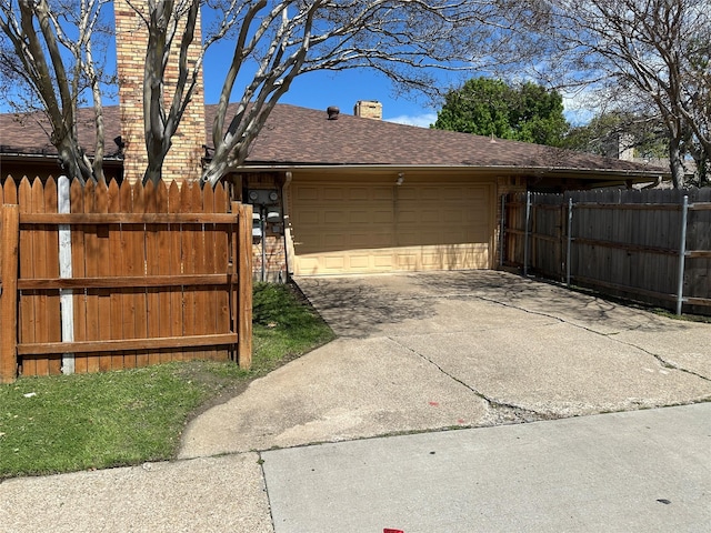 garage featuring concrete driveway, fence, and a gate