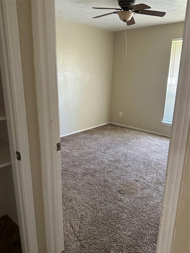 carpeted empty room featuring baseboards, a ceiling fan, and a textured ceiling