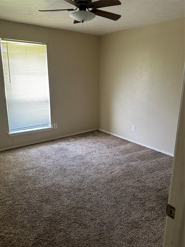 carpeted spare room featuring baseboards, ceiling fan, and a wealth of natural light