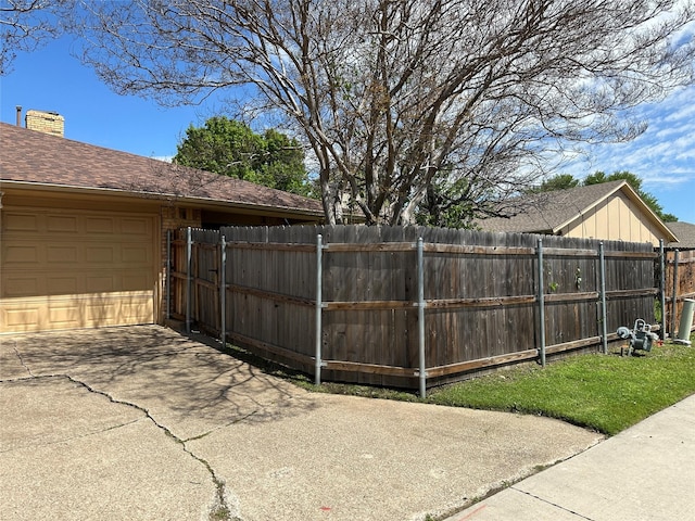 view of yard with a garage, fence, and driveway
