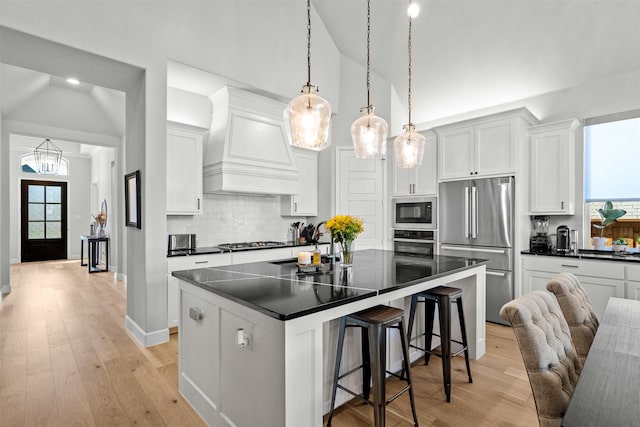 kitchen featuring dark countertops, premium range hood, stainless steel appliances, and lofted ceiling