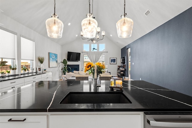 kitchen featuring stainless steel dishwasher, a sink, visible vents, and dark countertops