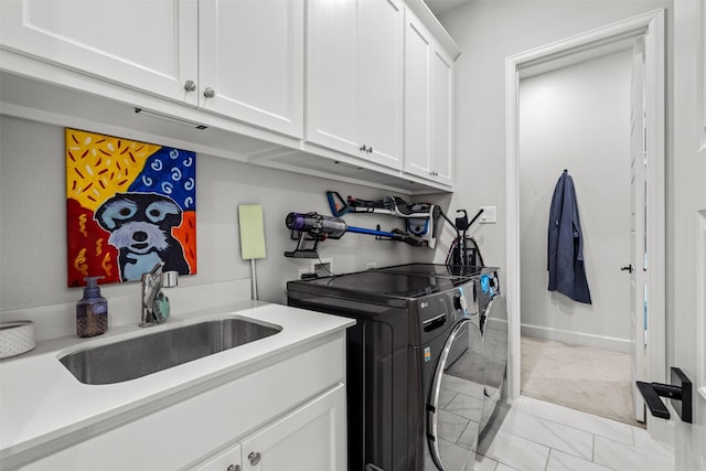washroom with separate washer and dryer, a sink, cabinet space, and baseboards