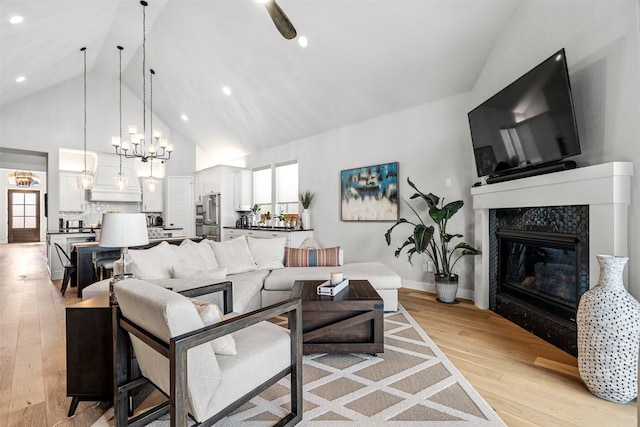 living area featuring light wood finished floors, a fireplace, high vaulted ceiling, a chandelier, and recessed lighting