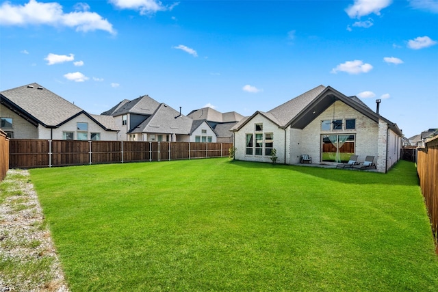 back of property with a yard, a residential view, and a fenced backyard