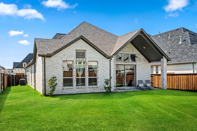 rear view of property featuring a yard, central AC, a fenced backyard, and roof with shingles