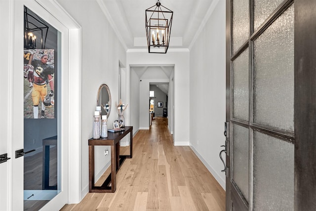entryway featuring an inviting chandelier, ornamental molding, light wood-style flooring, and baseboards