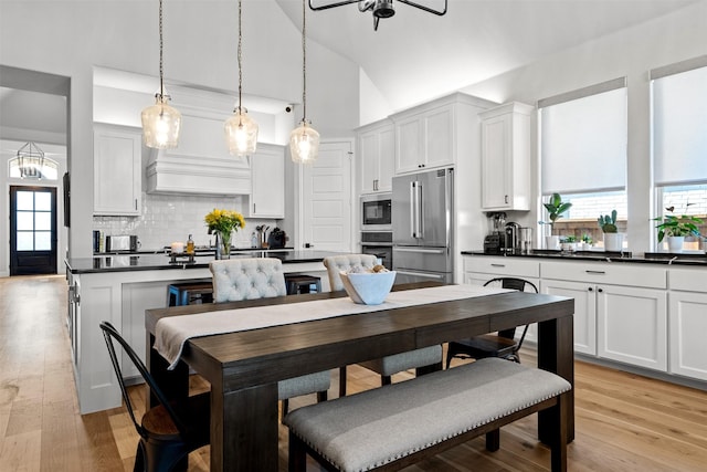 dining space with light wood-style flooring, lofted ceiling, and a wealth of natural light