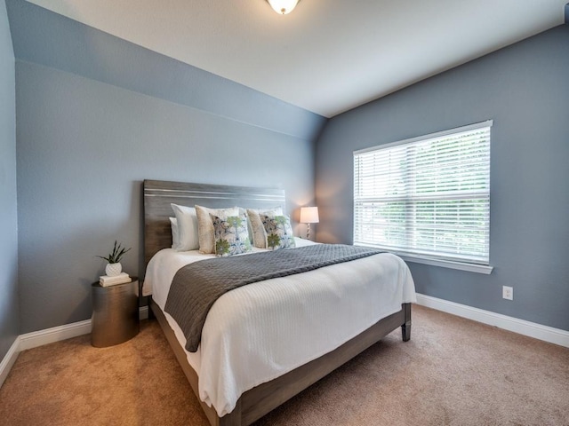 carpeted bedroom featuring baseboards and lofted ceiling