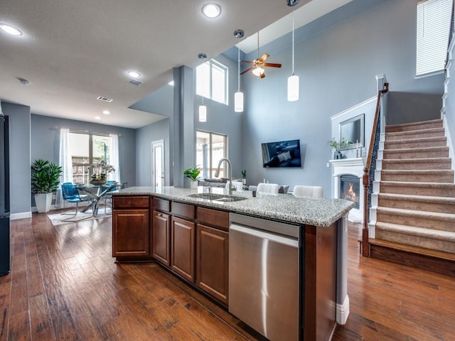 kitchen with dark wood-style flooring, a warm lit fireplace, a sink, a ceiling fan, and stainless steel dishwasher