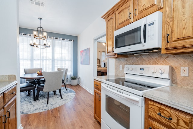 543 Islet Dr, Runaway Bay, TX 76426 - kitchen featuring white appliances, backsplash, light wood-style flooring, a chandelier, and brown cabinetry