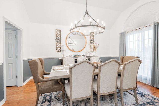 dining space featuring light wood-style floors, lofted ceiling, and a notable chandelier