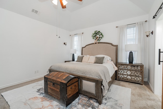 carpeted bedroom with a ceiling fan, vaulted ceiling, multiple windows, and visible vents