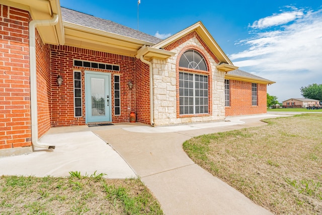 543 Islet Dr, Runaway Bay, TX 76426 - property entrance with a shingled roof, brick siding, stone siding, and a lawn