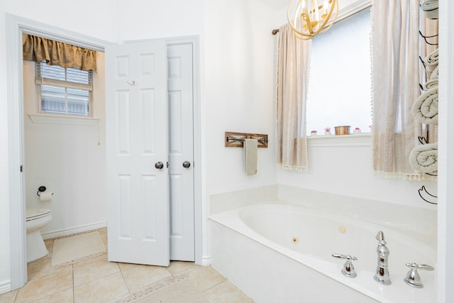 full bath featuring a tub with jets, baseboards, tile patterned floors, and toilet
