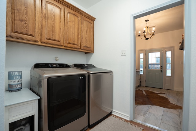 laundry room featuring an inviting chandelier, cabinet space, baseboards, and washing machine and clothes dryer
