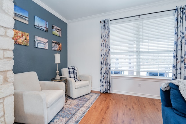 living area featuring baseboards, ornamental molding, and wood finished floors