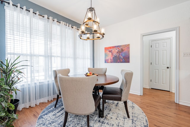dining area with baseboards, light wood finished floors, and a chandelier