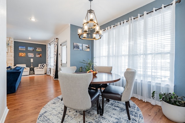 dining room with an inviting chandelier, ornamental molding, baseboards, and wood finished floors