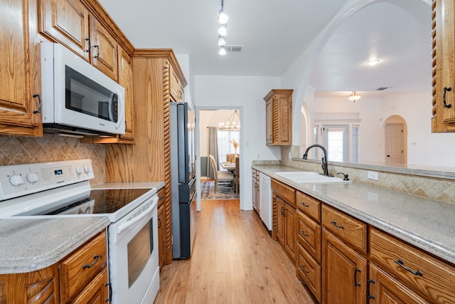kitchen with a sink, brown cabinets, decorative backsplash, and white appliances
