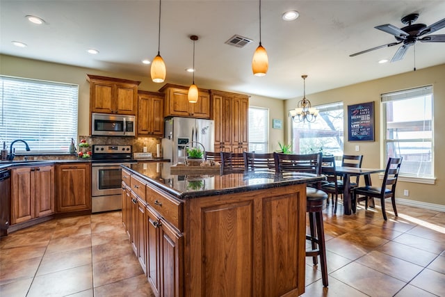 kitchen with a kitchen breakfast bar, visible vents, appliances with stainless steel finishes, brown cabinets, and a sink