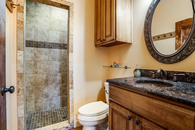 bathroom with vanity, a tile shower, and toilet