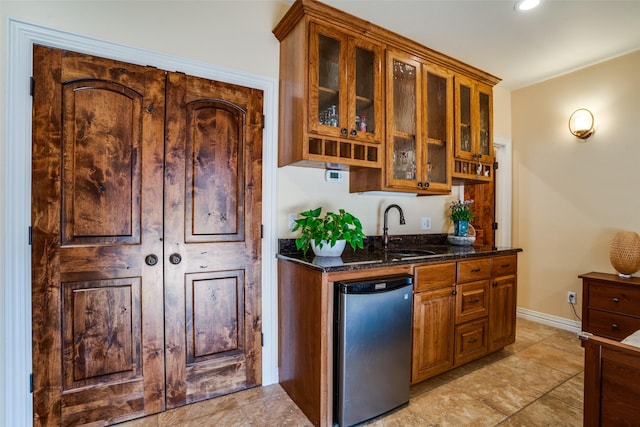 bar with indoor wet bar, fridge, baseboards, and a sink