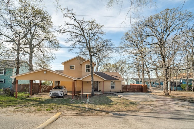 view of front of home with fence, a carport, and driveway