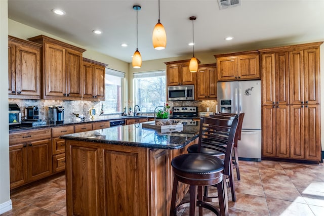 kitchen with decorative backsplash, stainless steel appliances, visible vents, and brown cabinetry